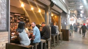 People drink, talk, and eat at a bar connected to a restaurant inside Krog Street Market