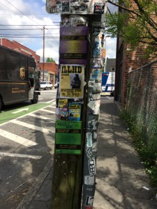 Pole on Edgewood Ave covered in flyers for open mic nights and performances in Department Store and around the city