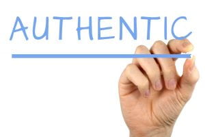 Picture of a hand writing the word authentic.