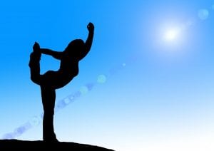 Silhouette of woman doing yoga on blue sky background 