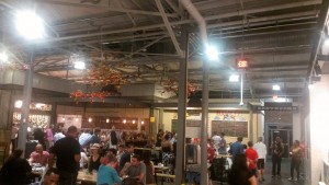 People eating and socializing inside Krog Street Market with view of exposed ceiling and pipes
